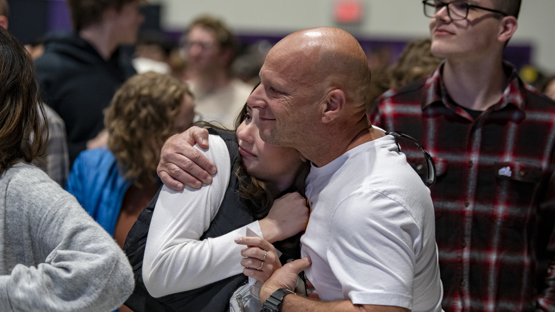 proud bald caucasian father hugs daughter at spring welcome seminar