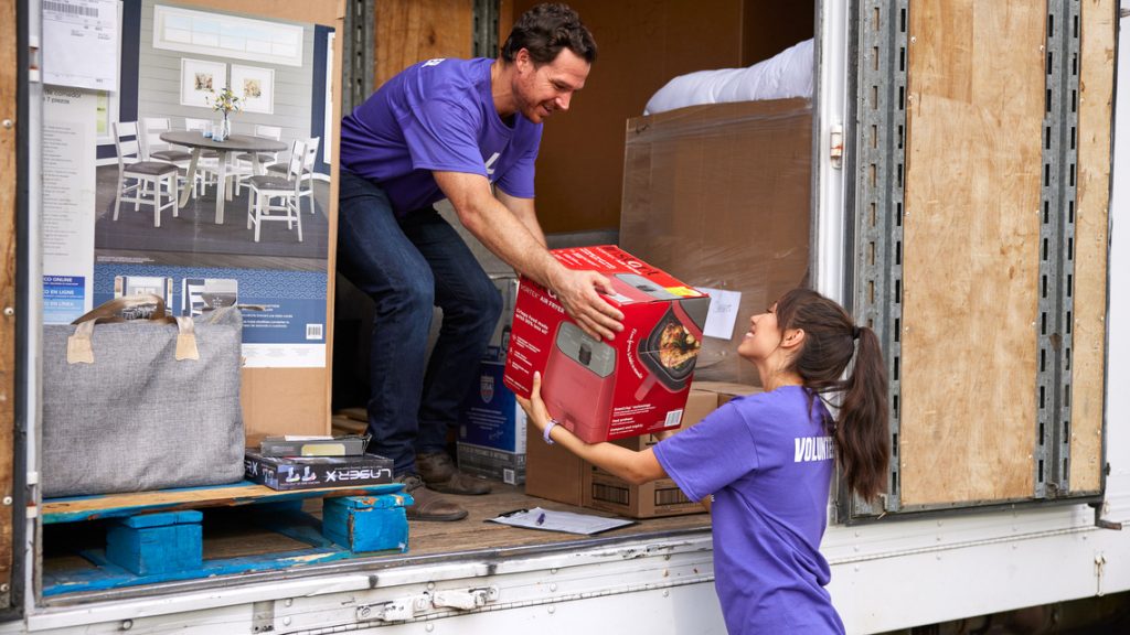 Brunette girl takes box from someone in back of a box truck for a CityServe volunteer event